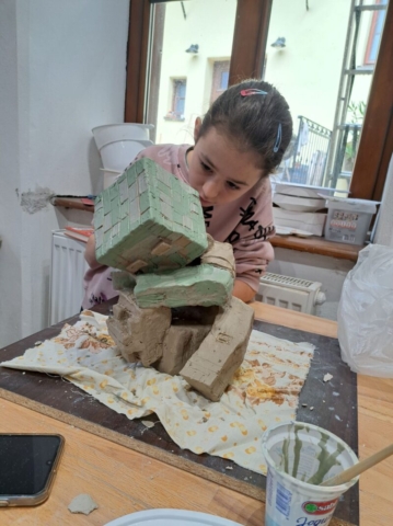 Natália nanáša engobu na svoju plastiku